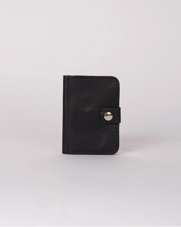 A small black leather card holder or wallet with a snap button closure, standing upright on a light gray background.