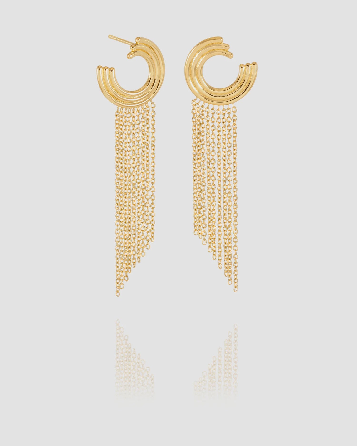 Gold hoop earrings with chain tassels on a light gray background