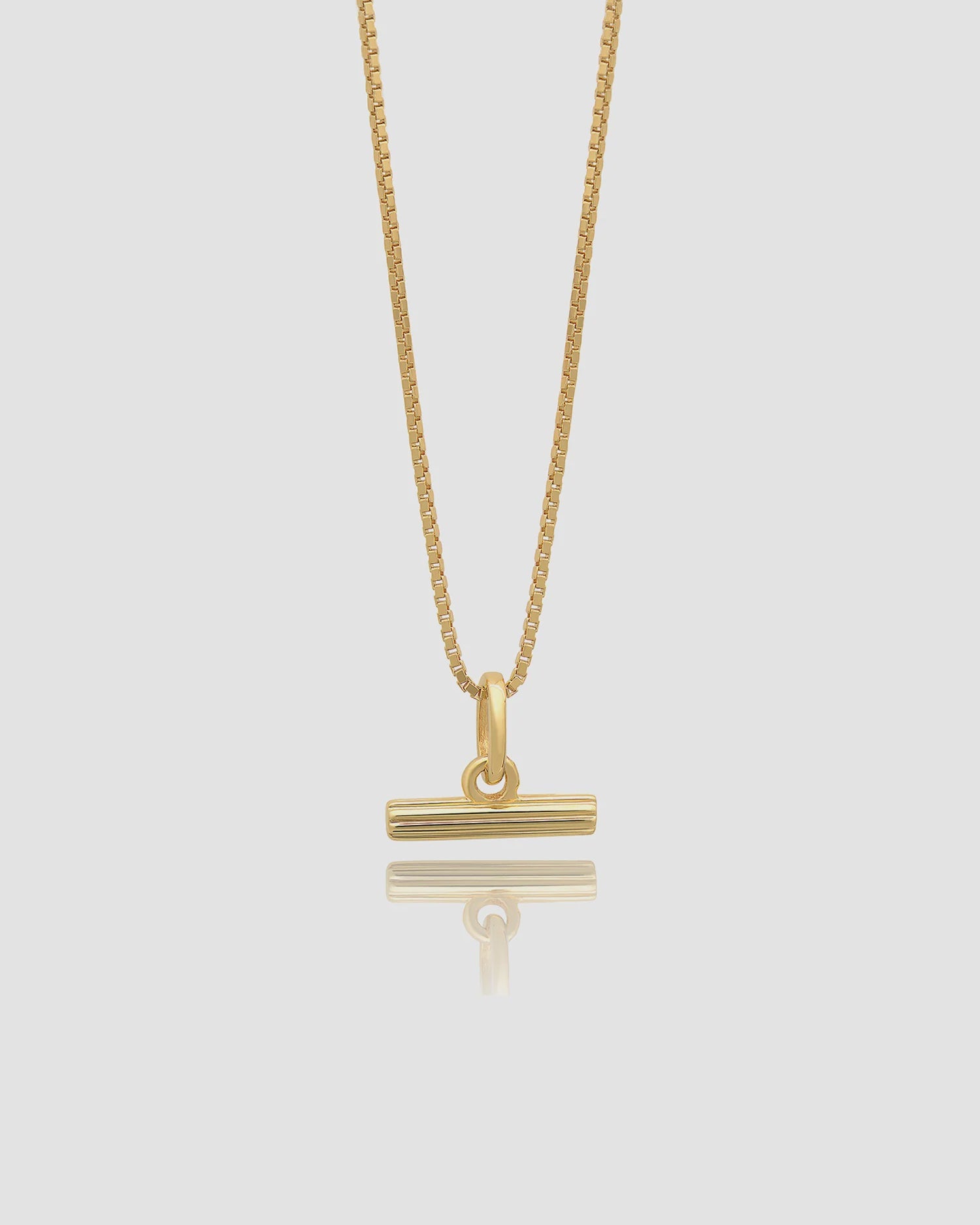 Gold necklace with a unique pendant on a light gray background