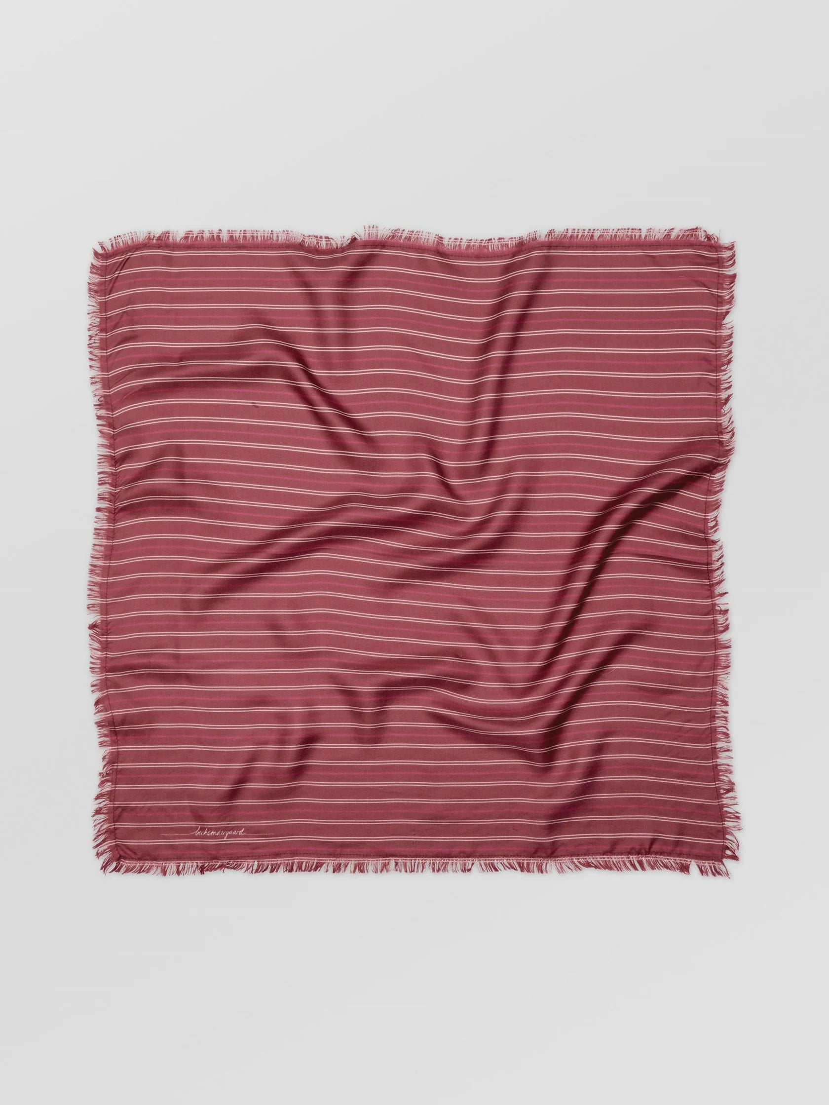 Striped fabric square with frayed edges on a light gray background