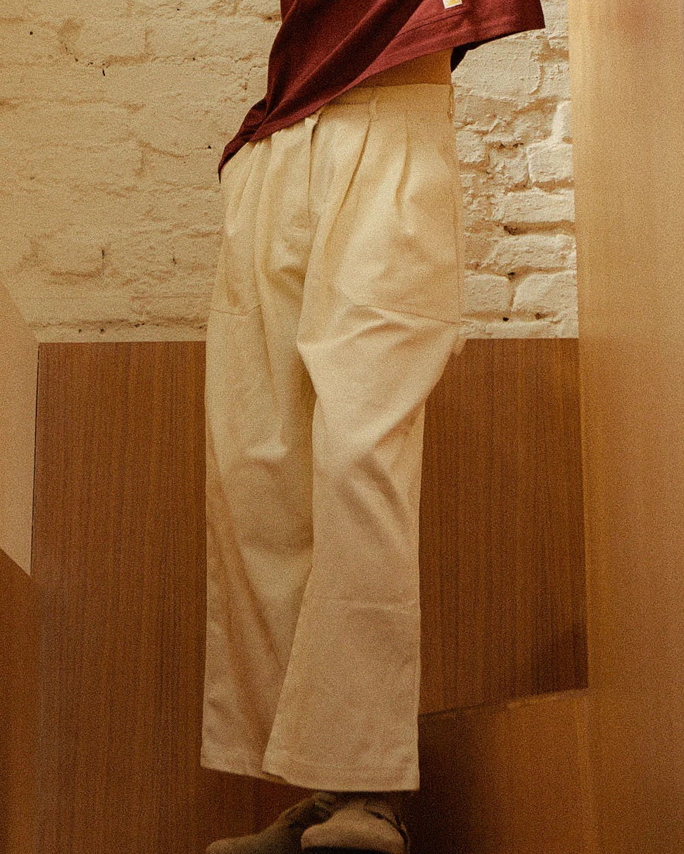 Person wearing beige pants and a maroon top against a stone wall.