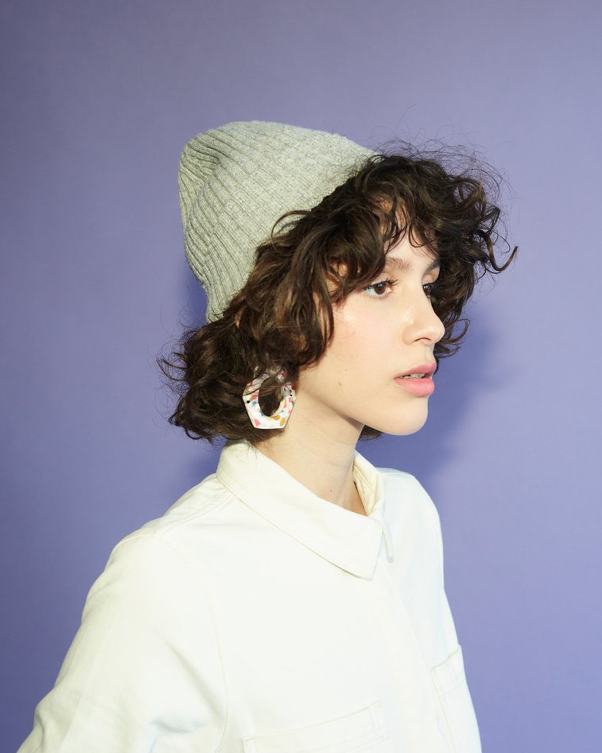 Person wearing a knitted hat against a purple background