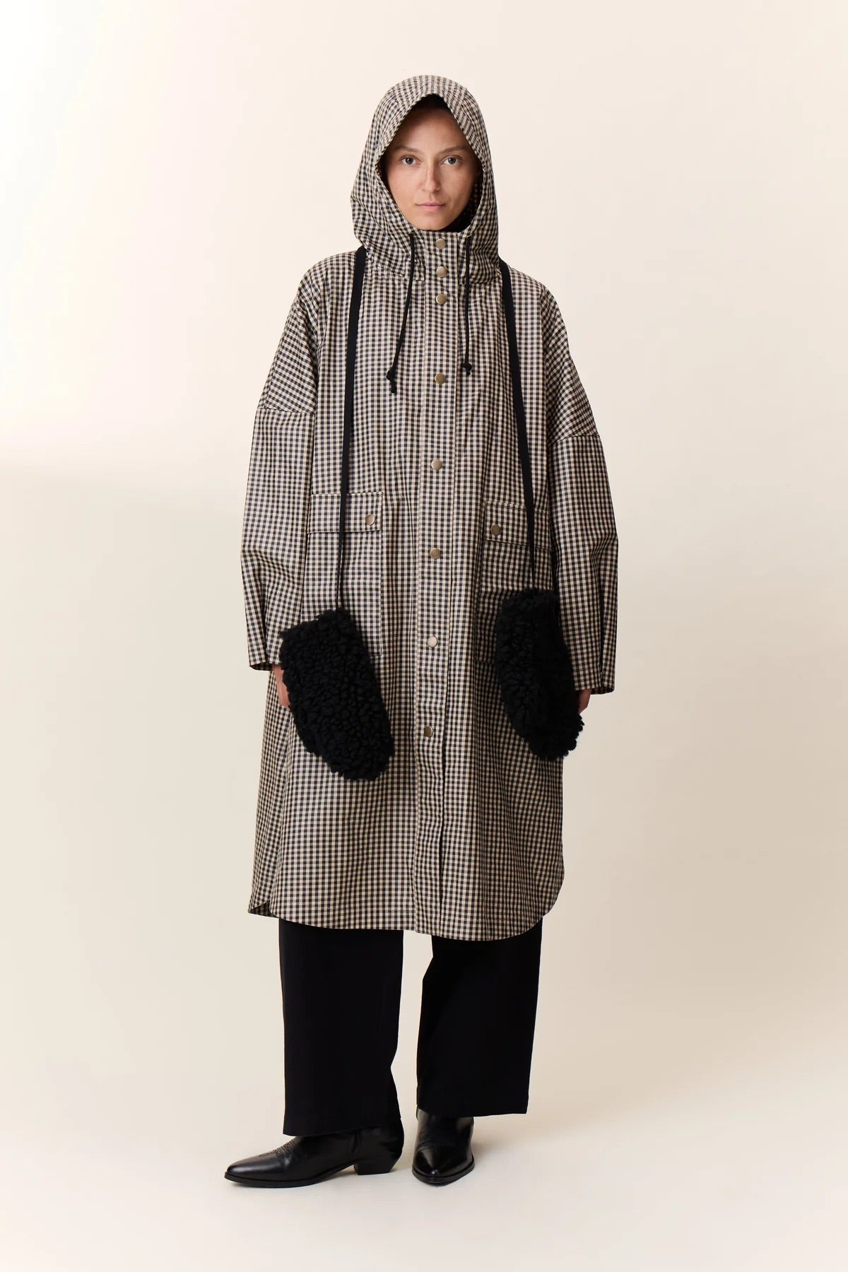 Person wearing a long checkered coat with a hood on a white background