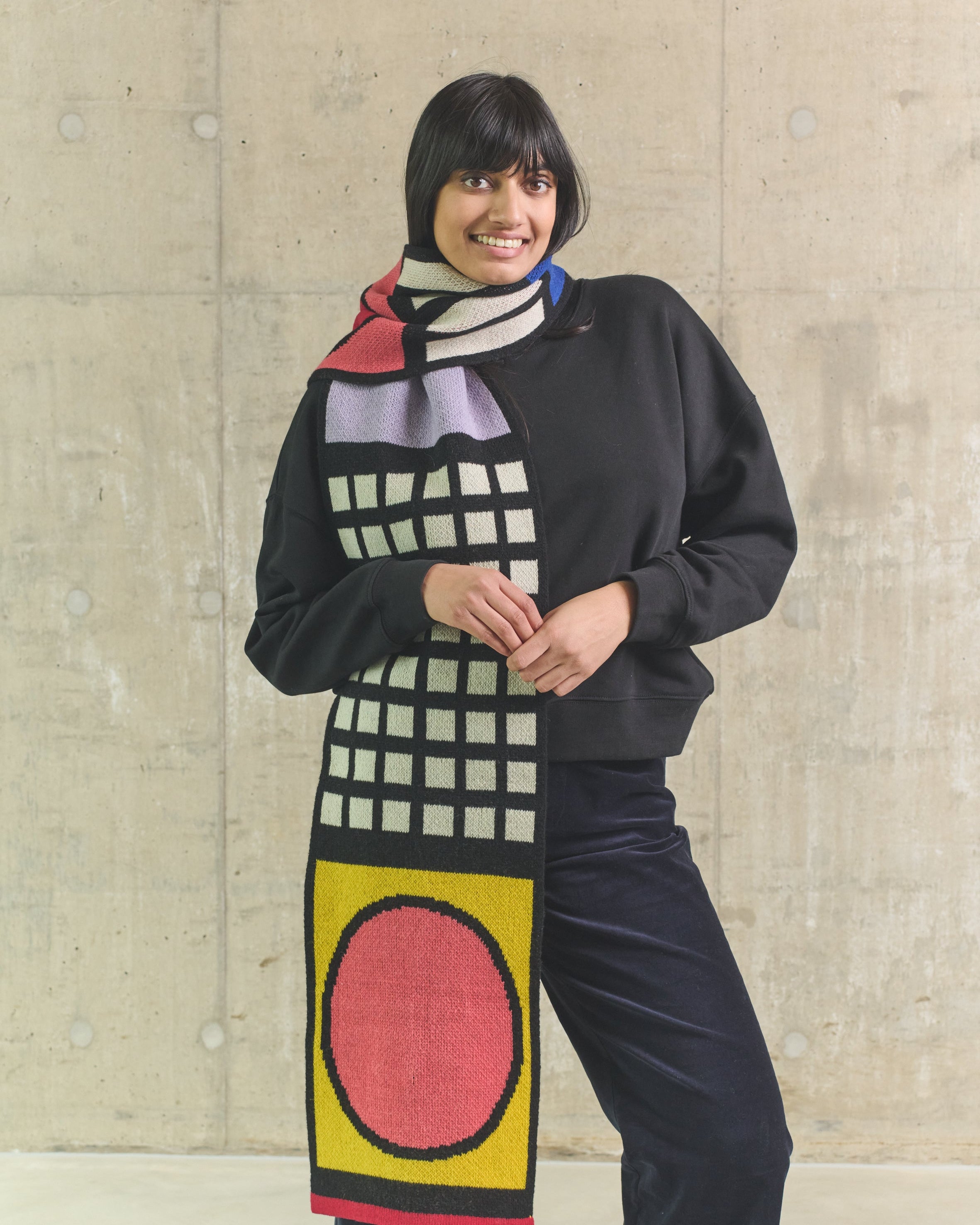 Person wearing a colorful scarf with geometric patterns against a plain background