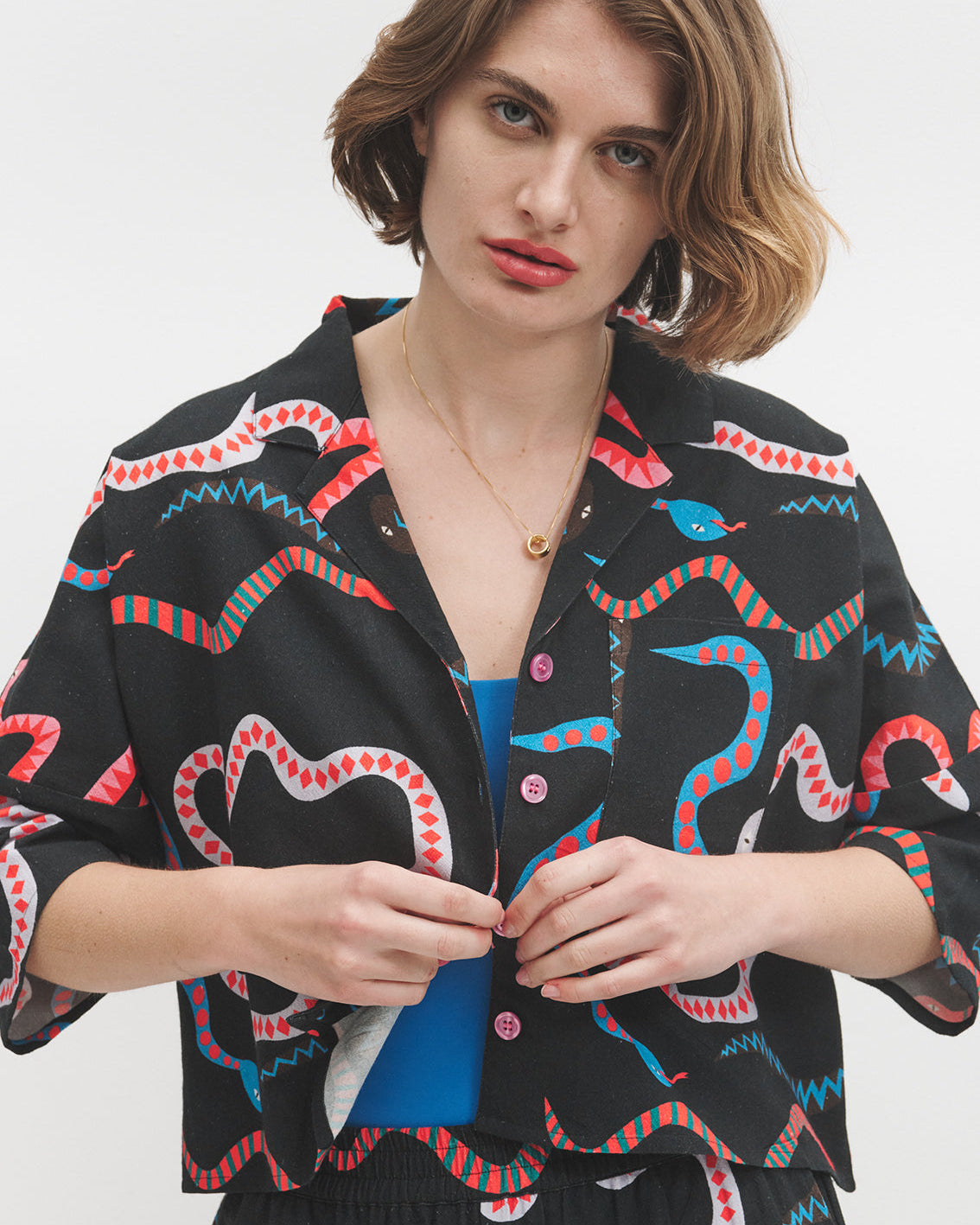 Woman wearing a black jacket with colorful snake patterns on a white background