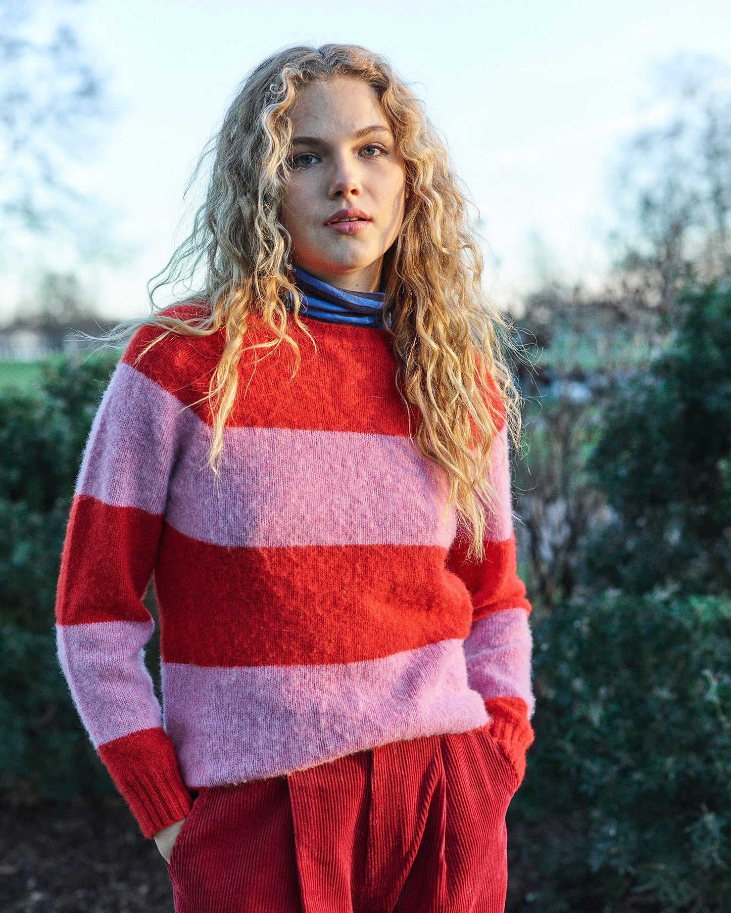 A striped Scottish jumper in pink and red with a round neckline and ribbed-knit hemline and trim around neck and wrist.
