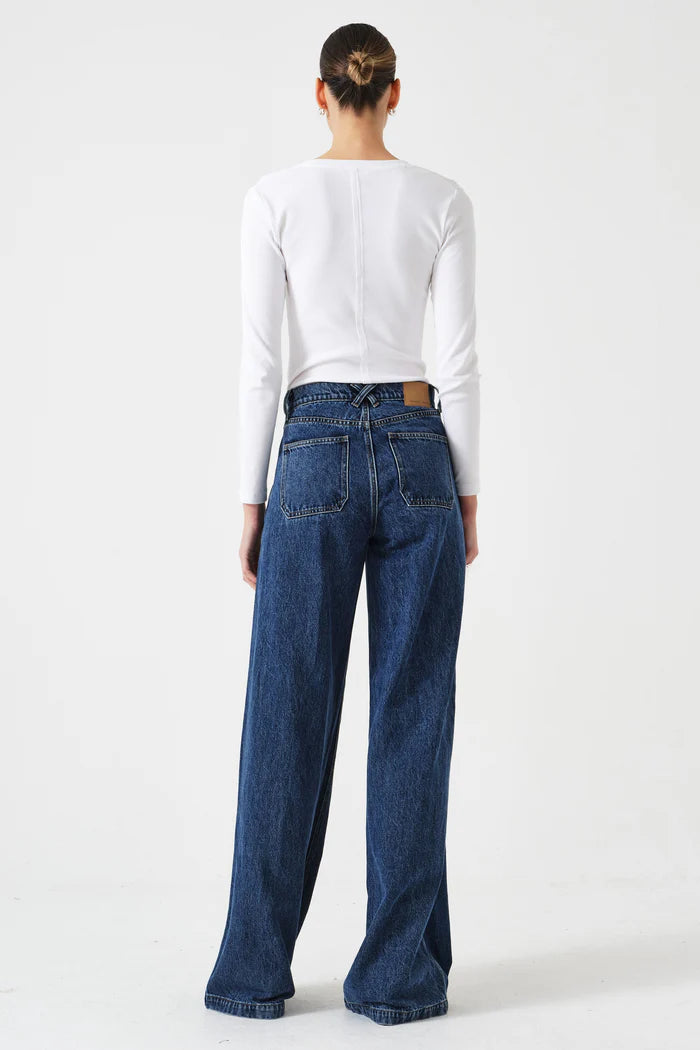 Person wearing blue jeans and a white long-sleeve shirt on a white background