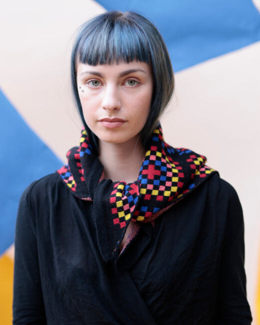 Person wearing a colorful checkered scarf against a geometric background