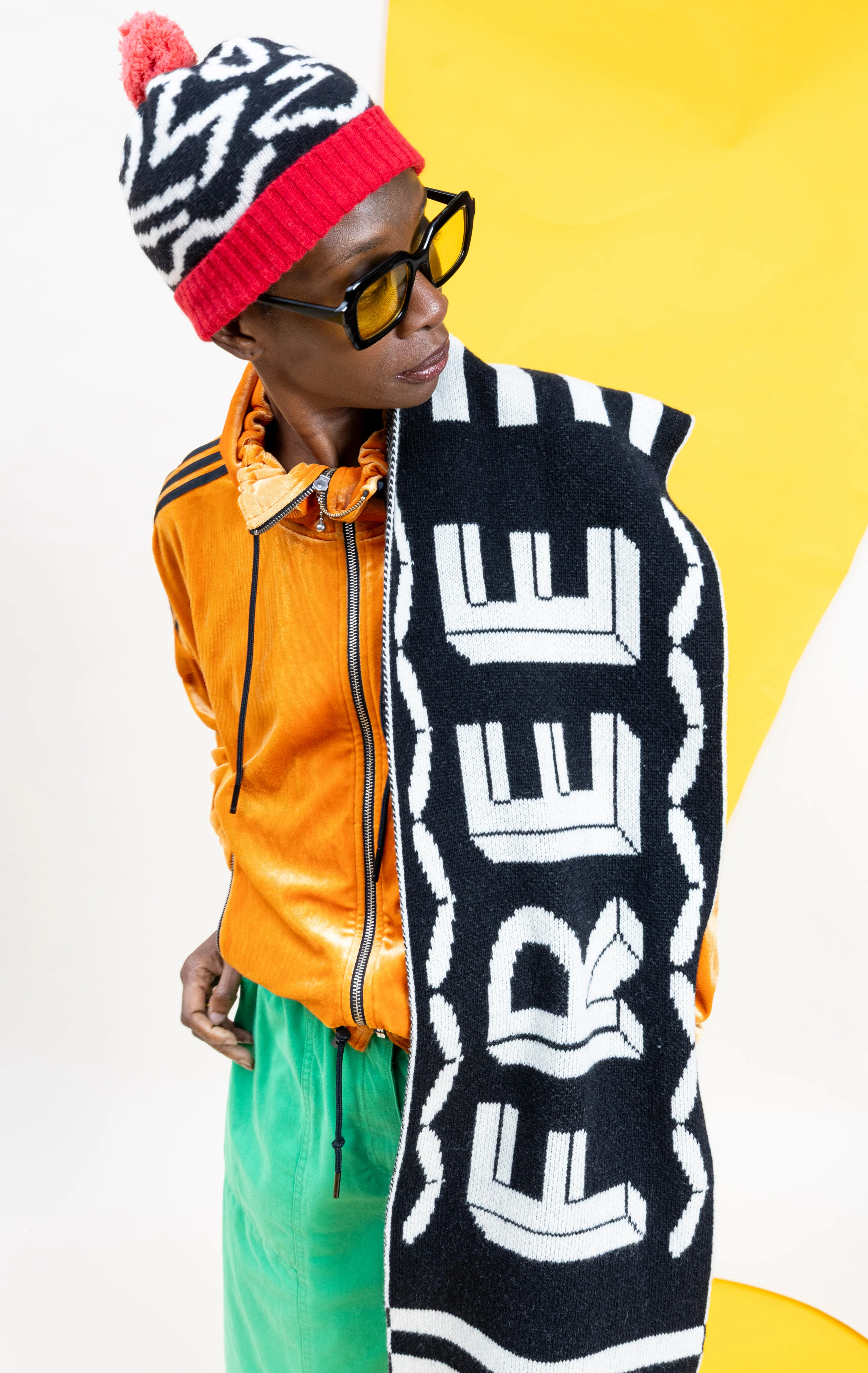 Person wearing a colorful outfit with a 'FREE' scarf against a yellow background