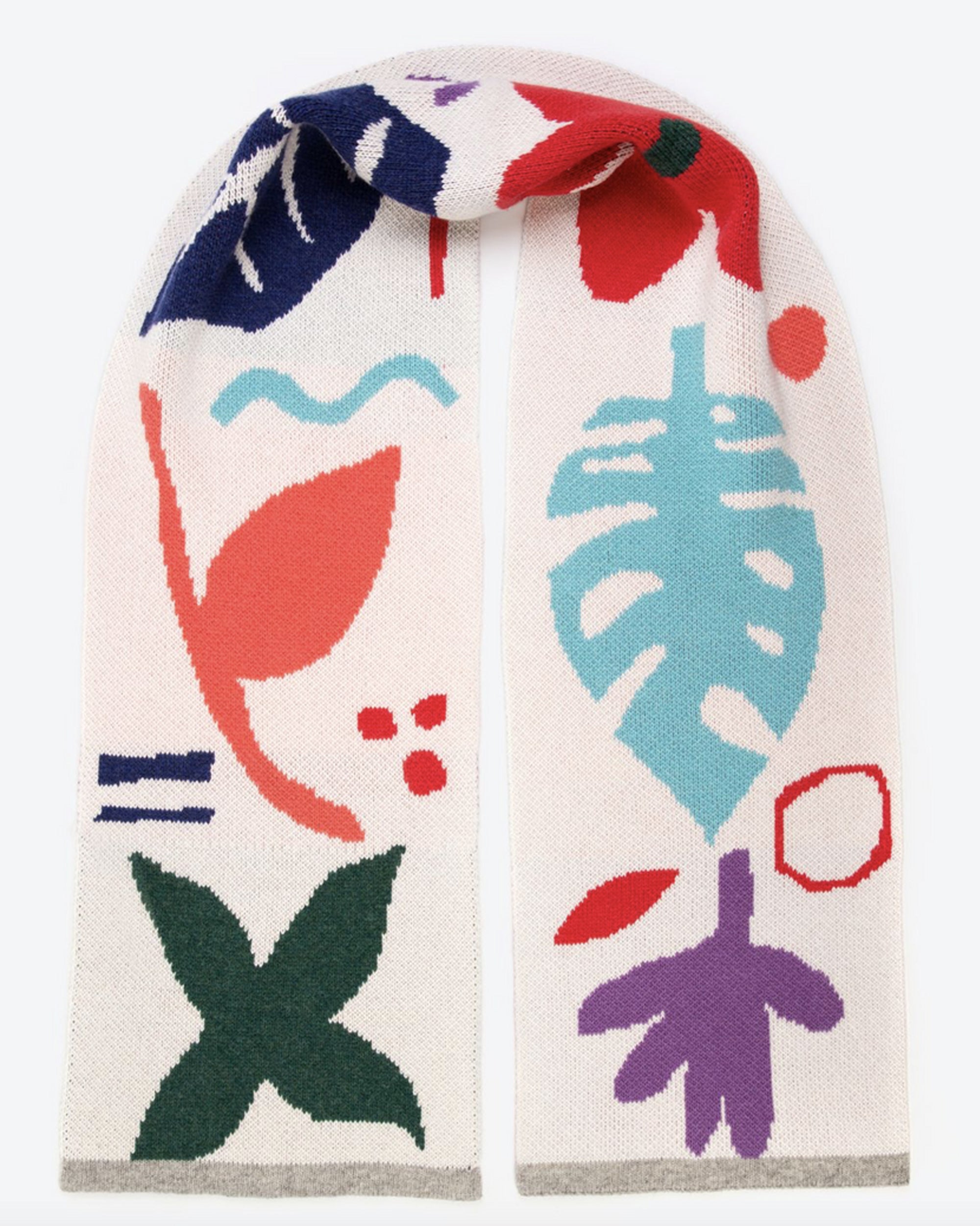 A cream wool scarf with a playful geometric and botanical pattern in multiple colors including green, red, blue, purple, pink, and turquoise, finished with a light grey edging.