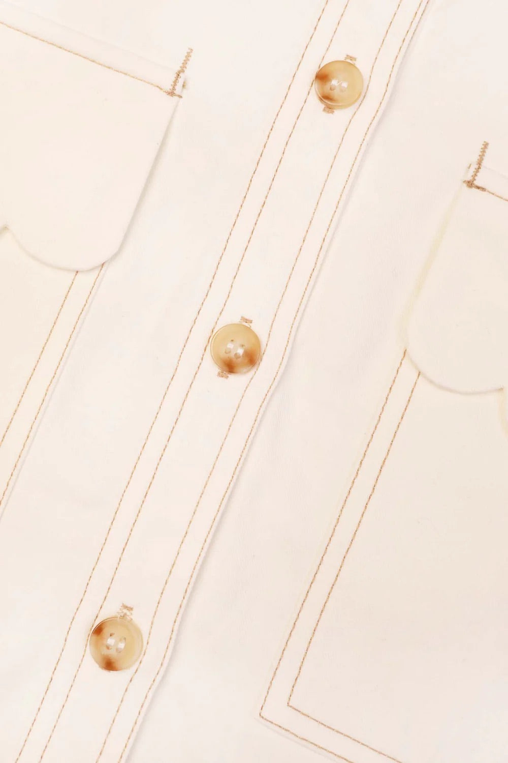 Close-up of a beige garment with buttons and stitching details