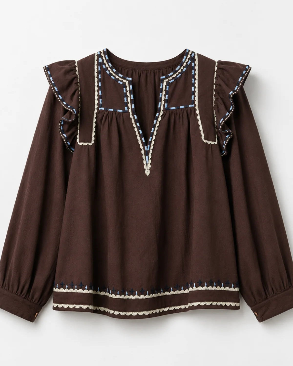 A dark brown long-sleeve blouse with ruffled shoulders and decorative embroidered trim in cream, blue, and white, shown against a light gray background.