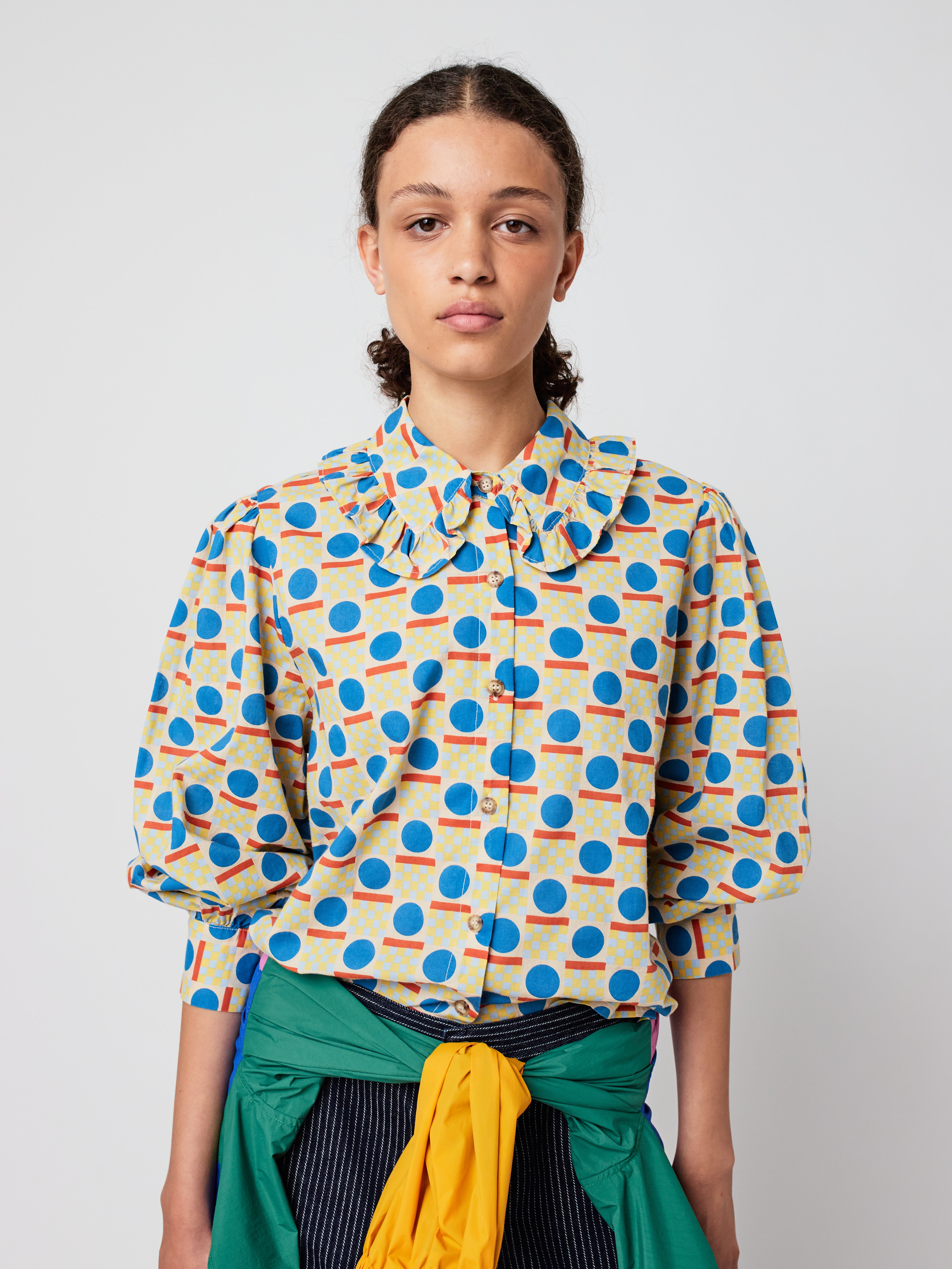 Woman wearing a colorful patterned blouse against a plain background