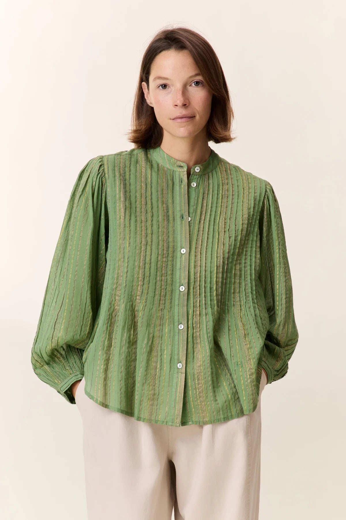 Woman wearing a green striped shirt against a plain background