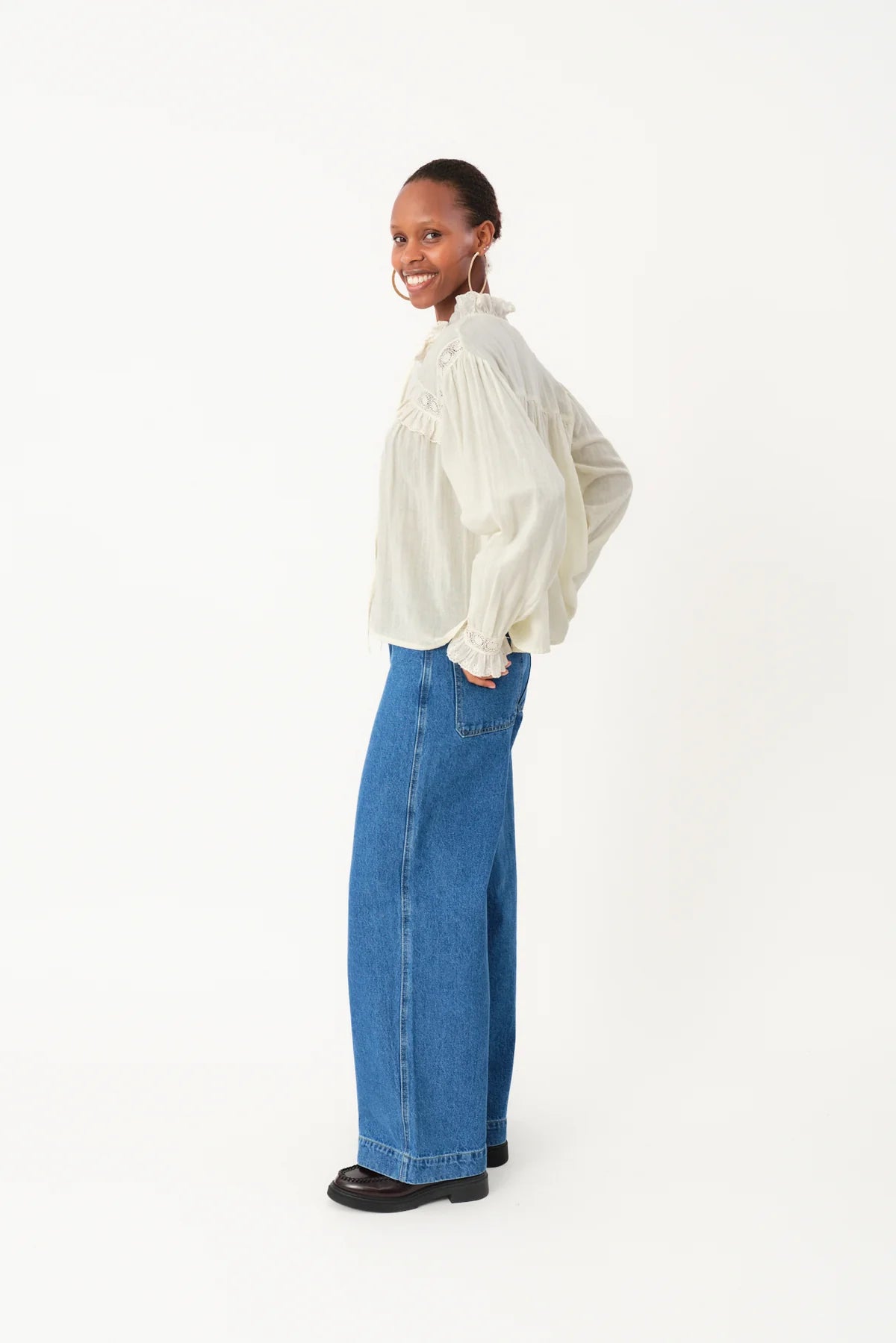 Person wearing a white blouse and blue jeans on a white background