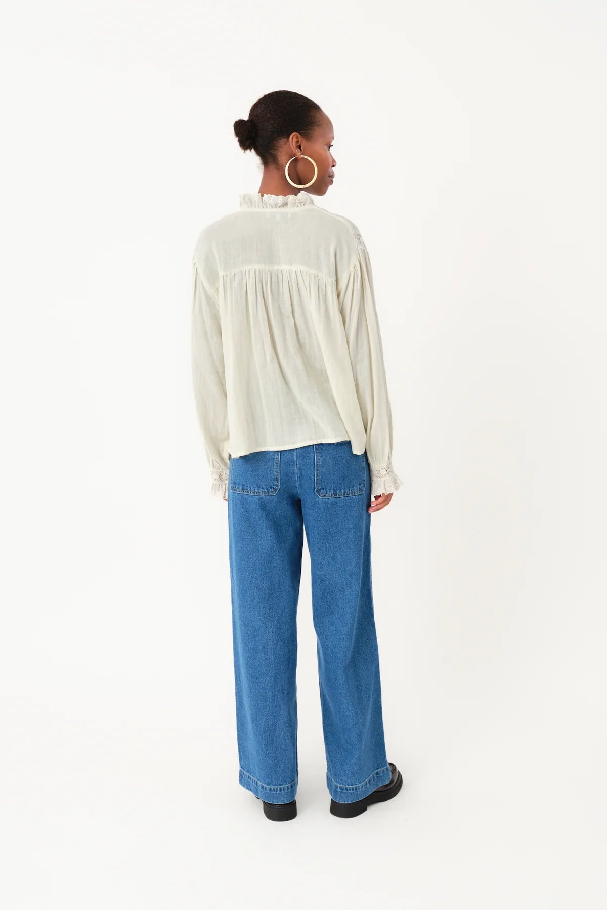 Person wearing a white blouse and blue jeans on a white background