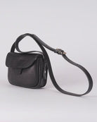 A small black leather crossbody bag with a long adjustable strap, shown on a light gray studio background.