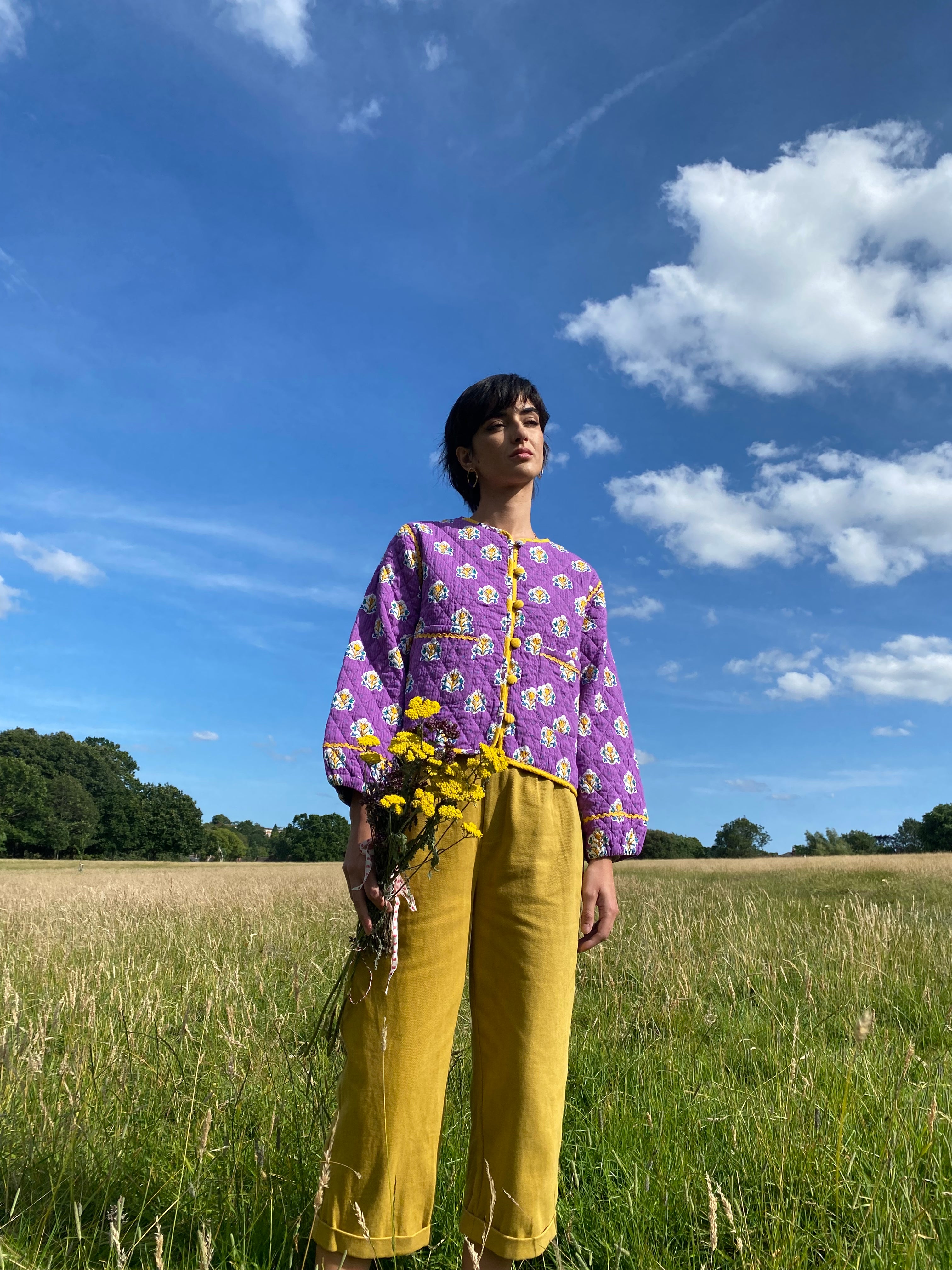 A pair of ochre pleat front trousers with a tab front opening and back jet pockets.