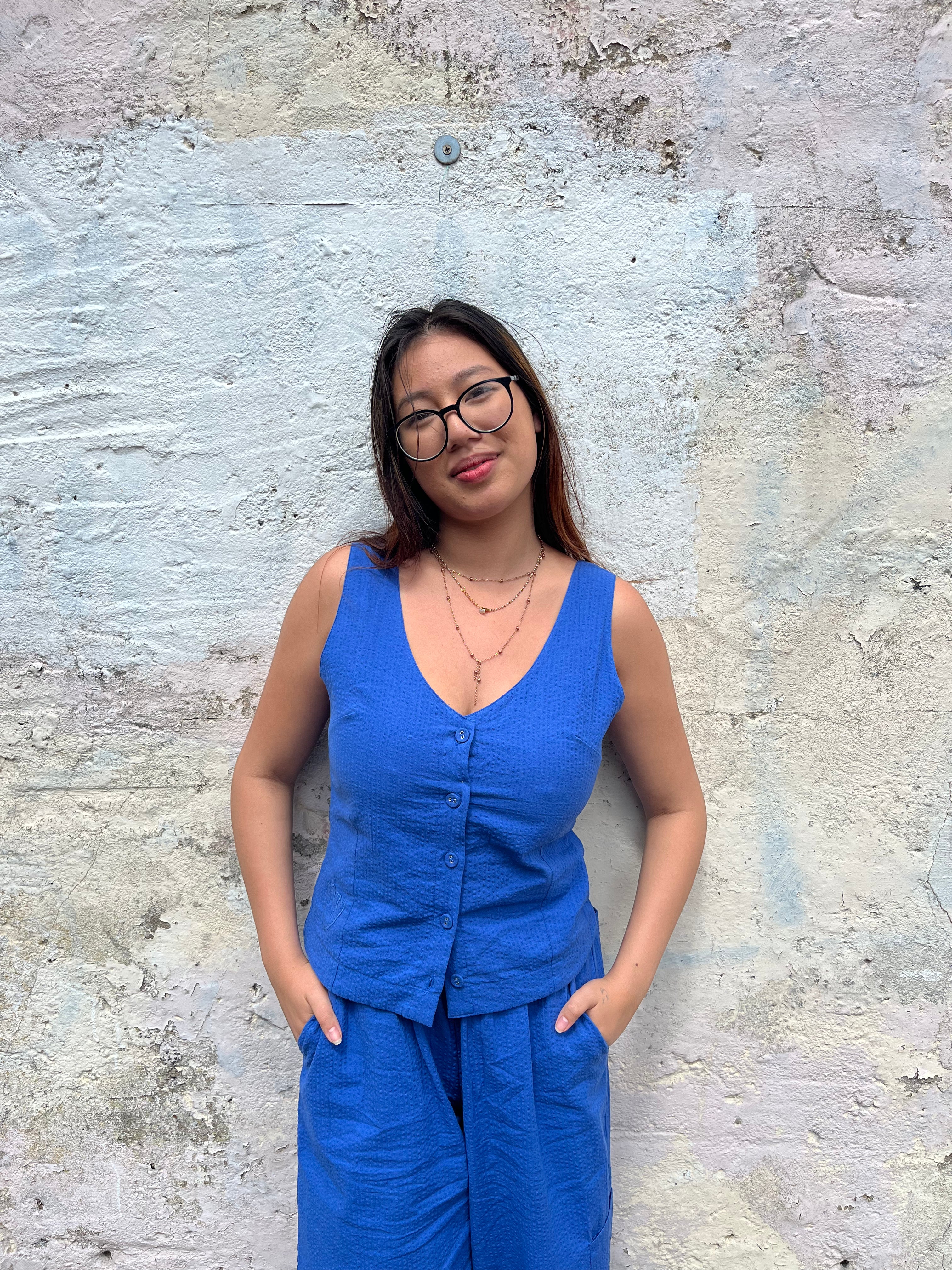 Woman in a blue outfit standing against a textured wall