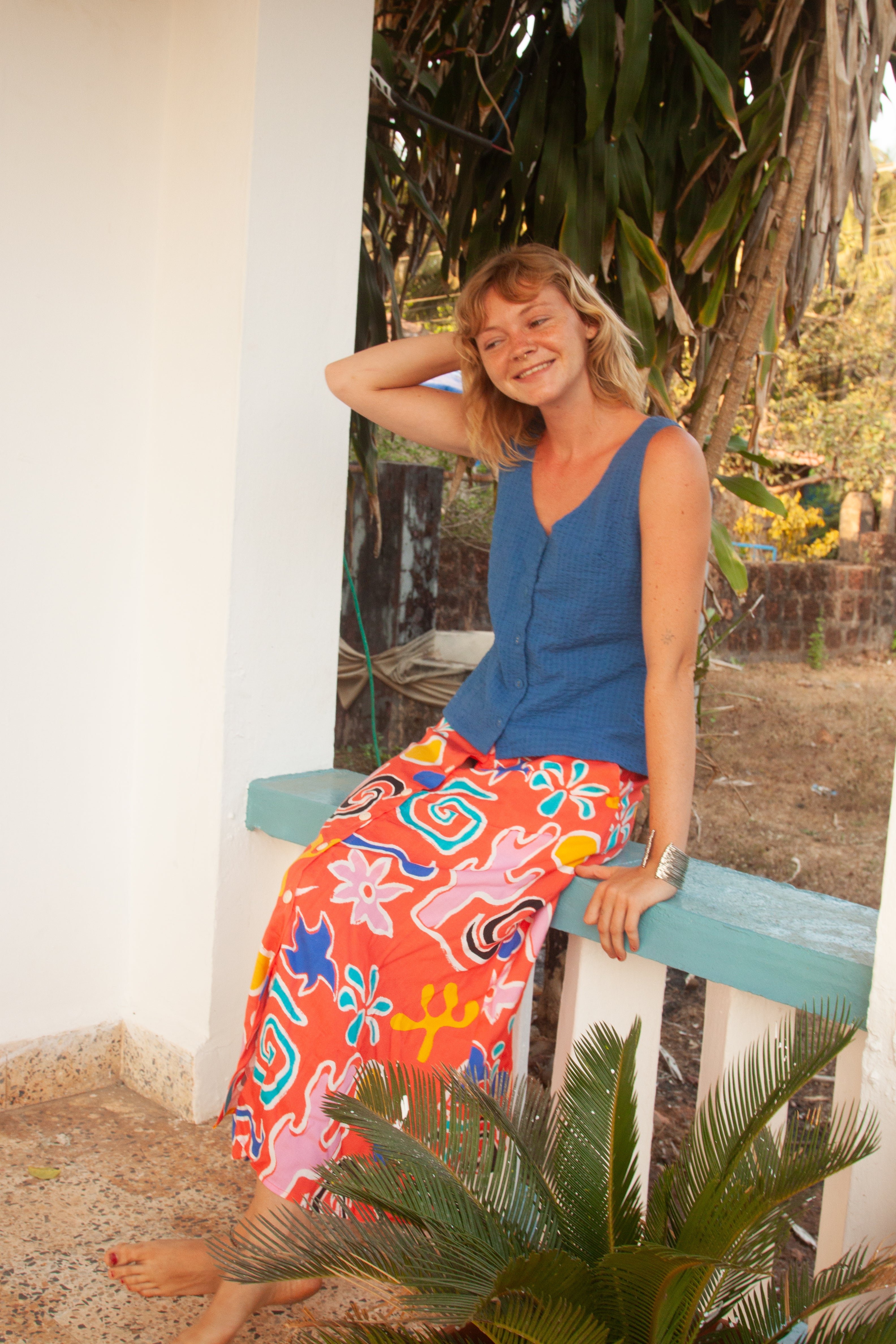 A midi-length orange skirt with a colorful abstract print, featuring side pockets and elasticated back waist.