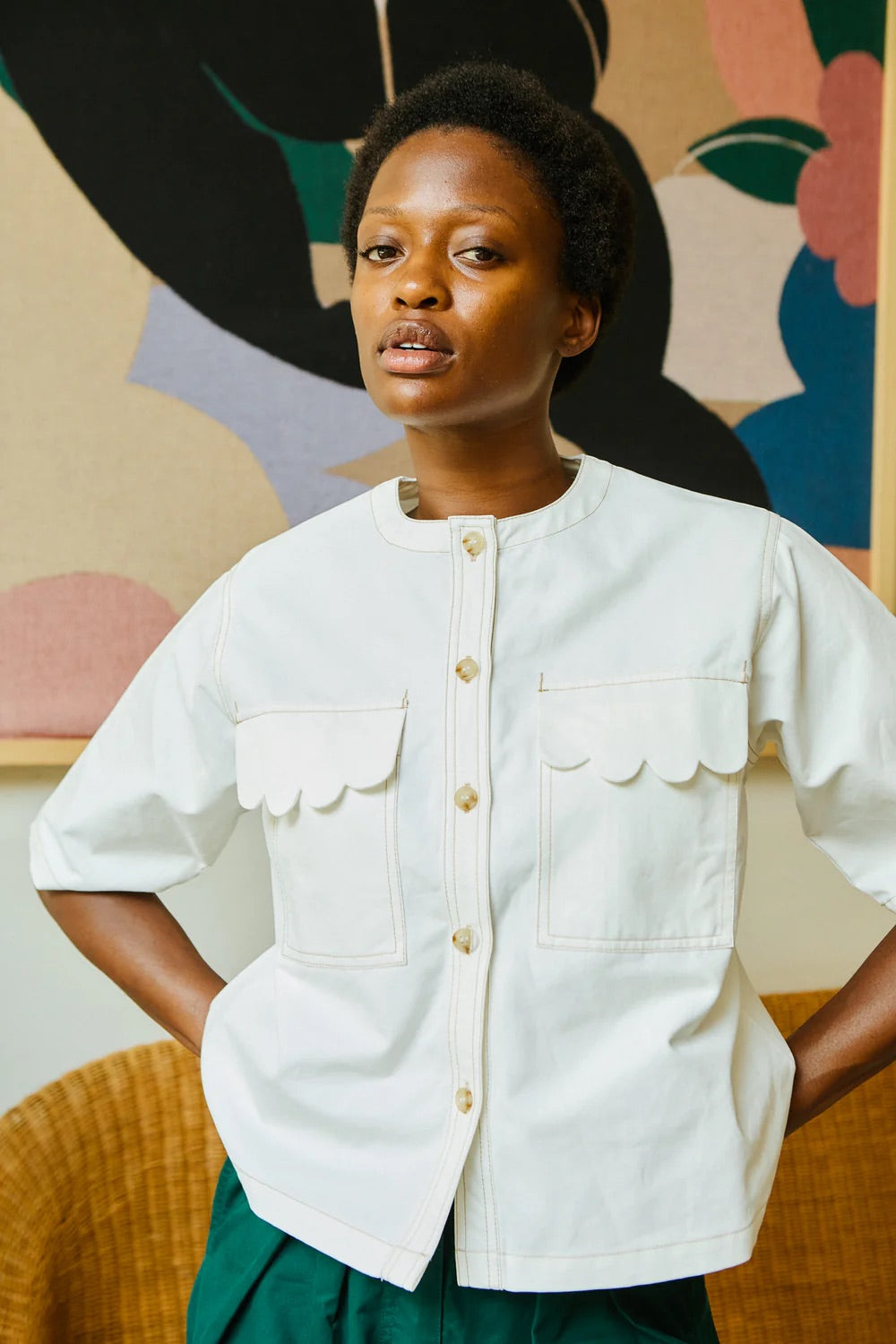 Woman wearing a white shirt with a colorful abstract painting in the background