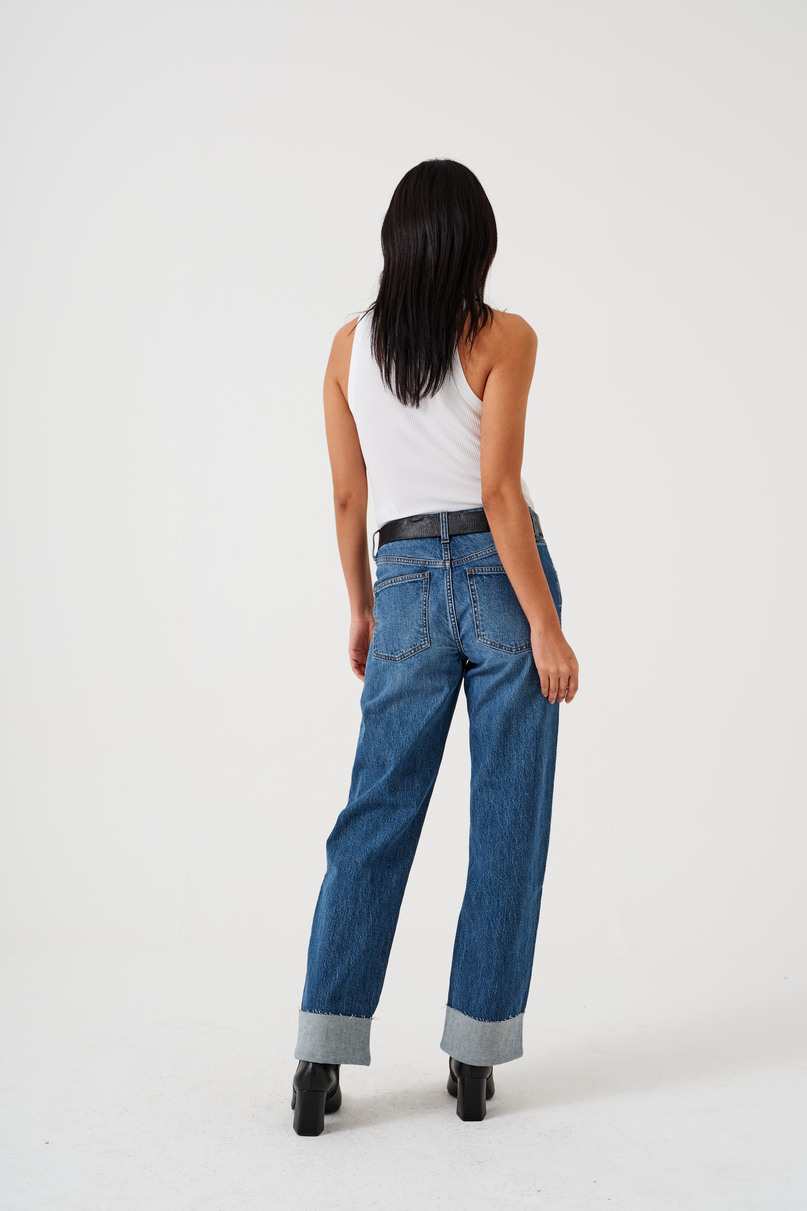 A pair of blue denim jeans with a frayed hem and a deep turn-up at the cuffs, featuring a straight leg cut and mid-rise waist.