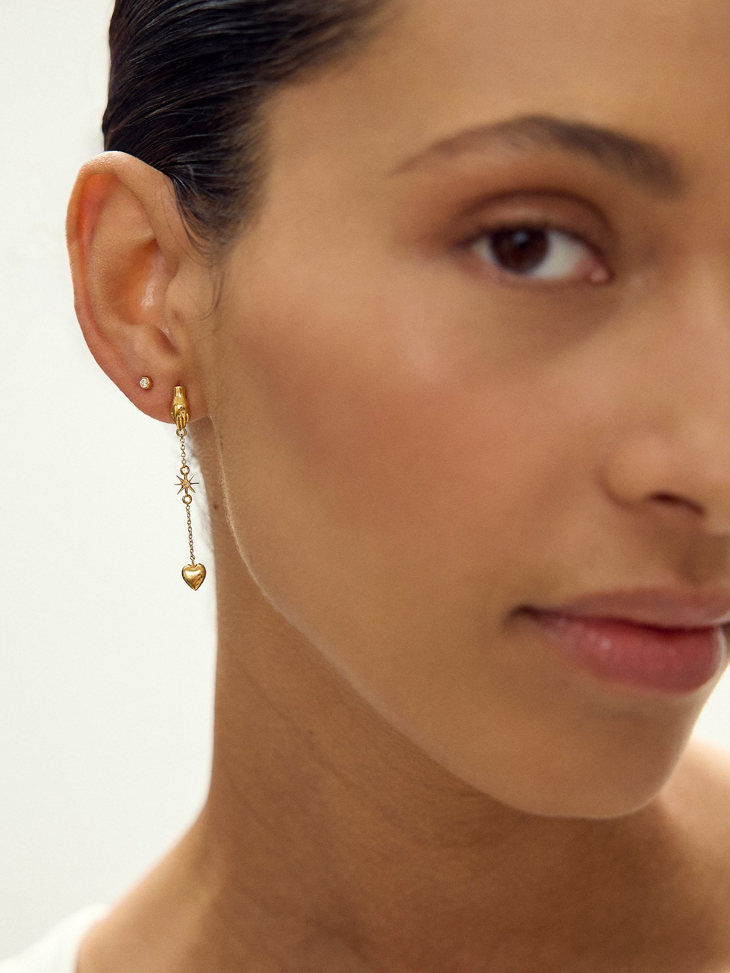 Close-up of a woman wearing gold earrings with a neutral background