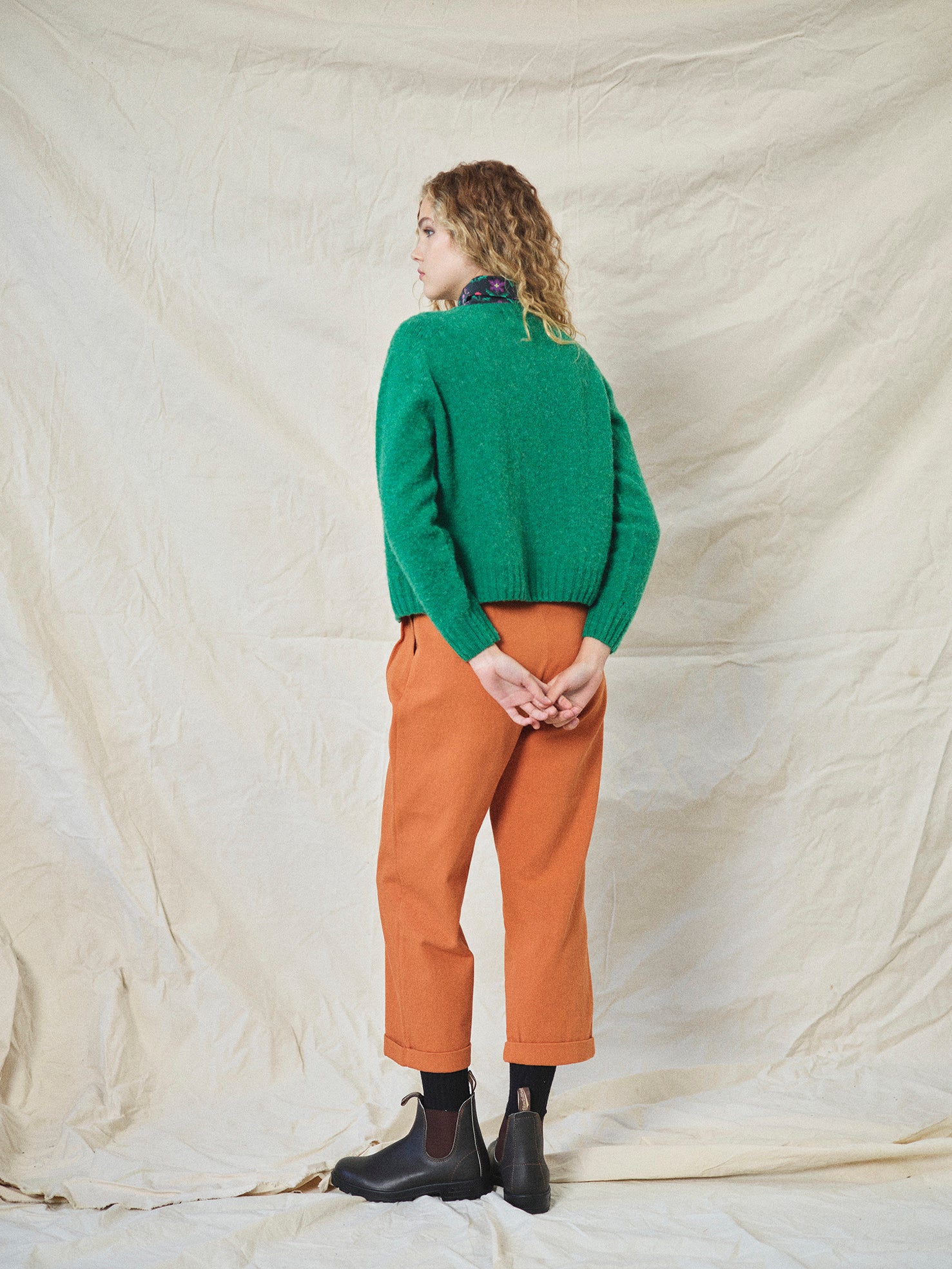 A pair of orange wide leg trousers with pleats and a fixed turn-up hem, made from cotton drill fabric.