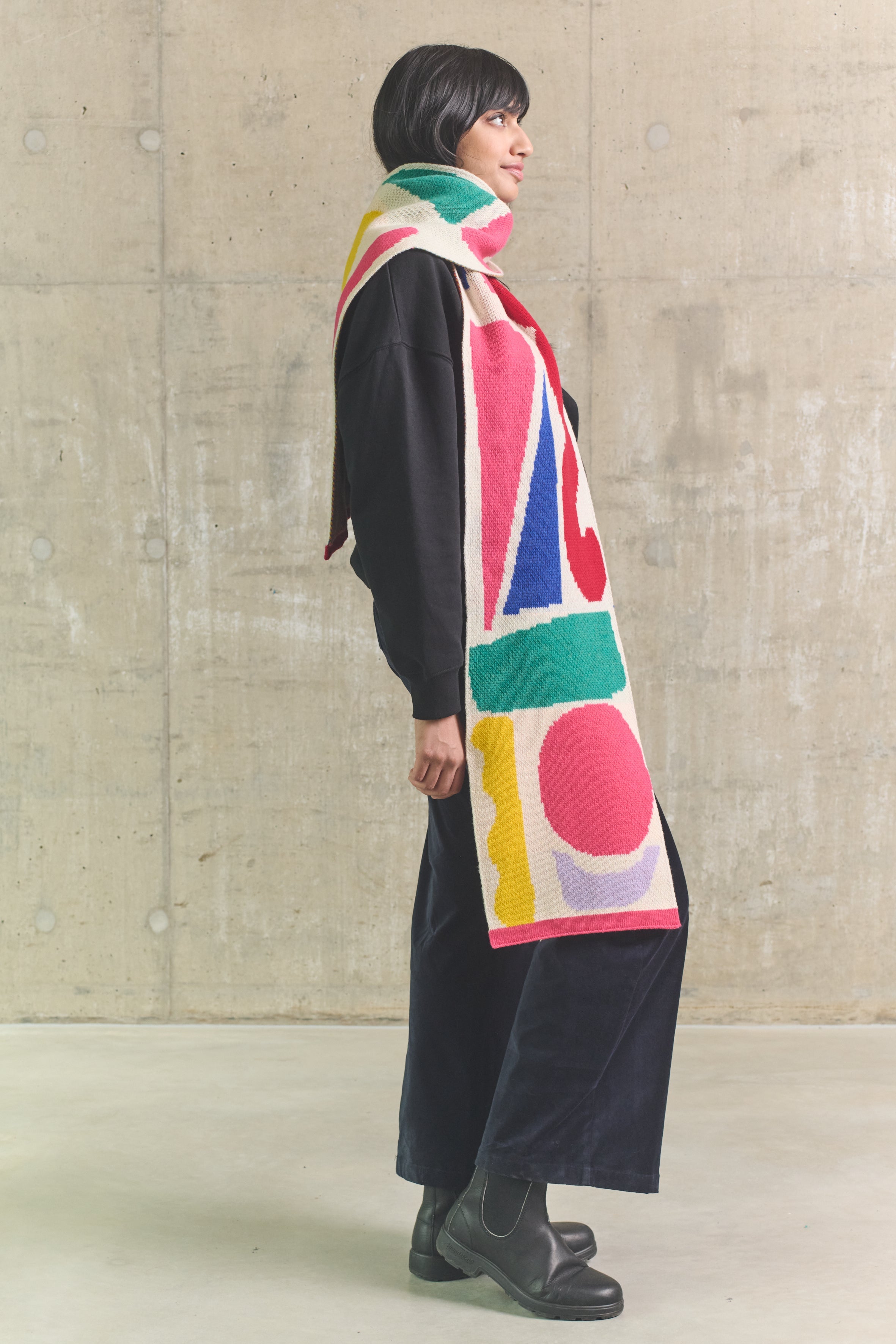 Person wearing a colorful scarf with abstract patterns against a plain background