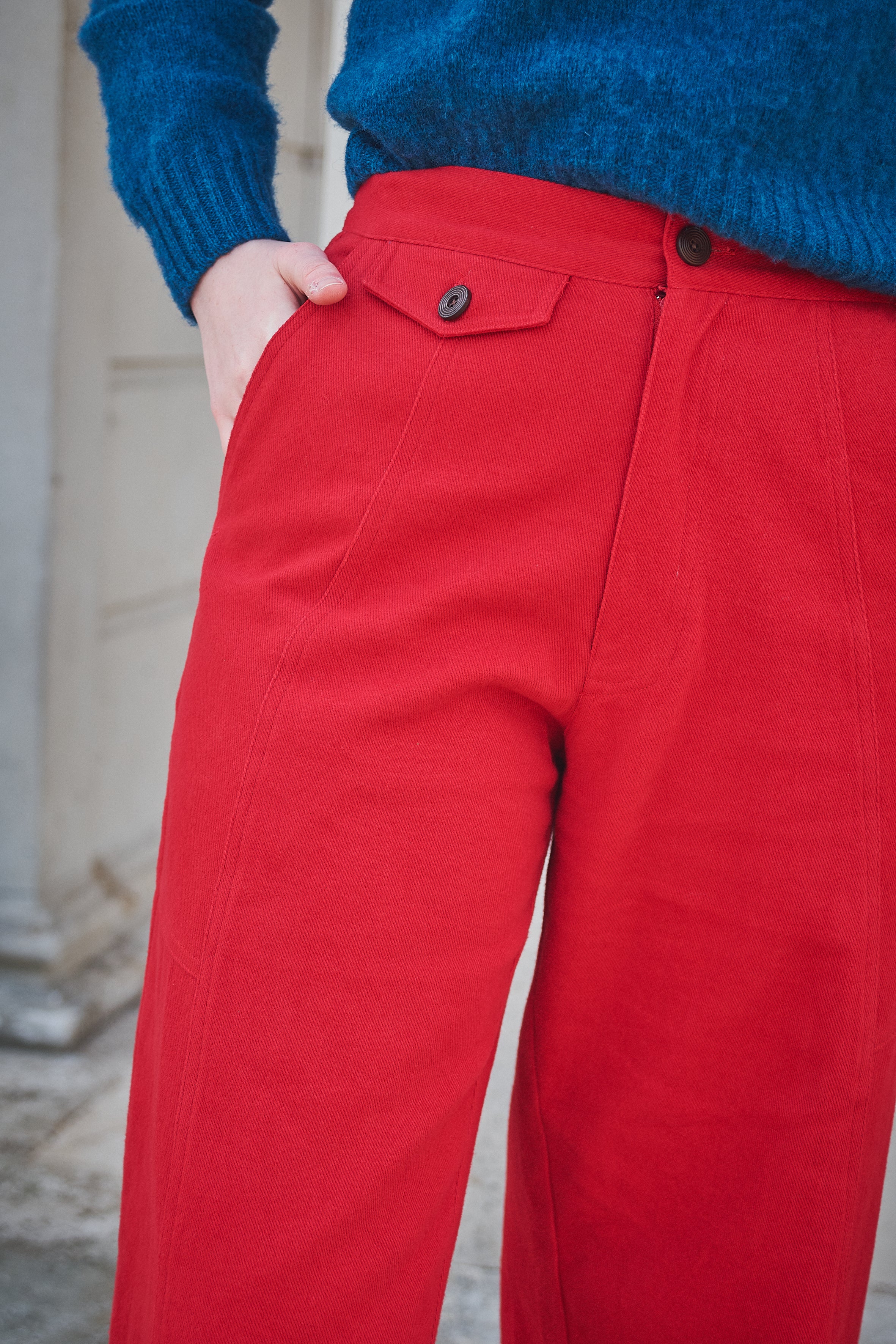 Red pants with a blue sweater worn by a person, blurred background