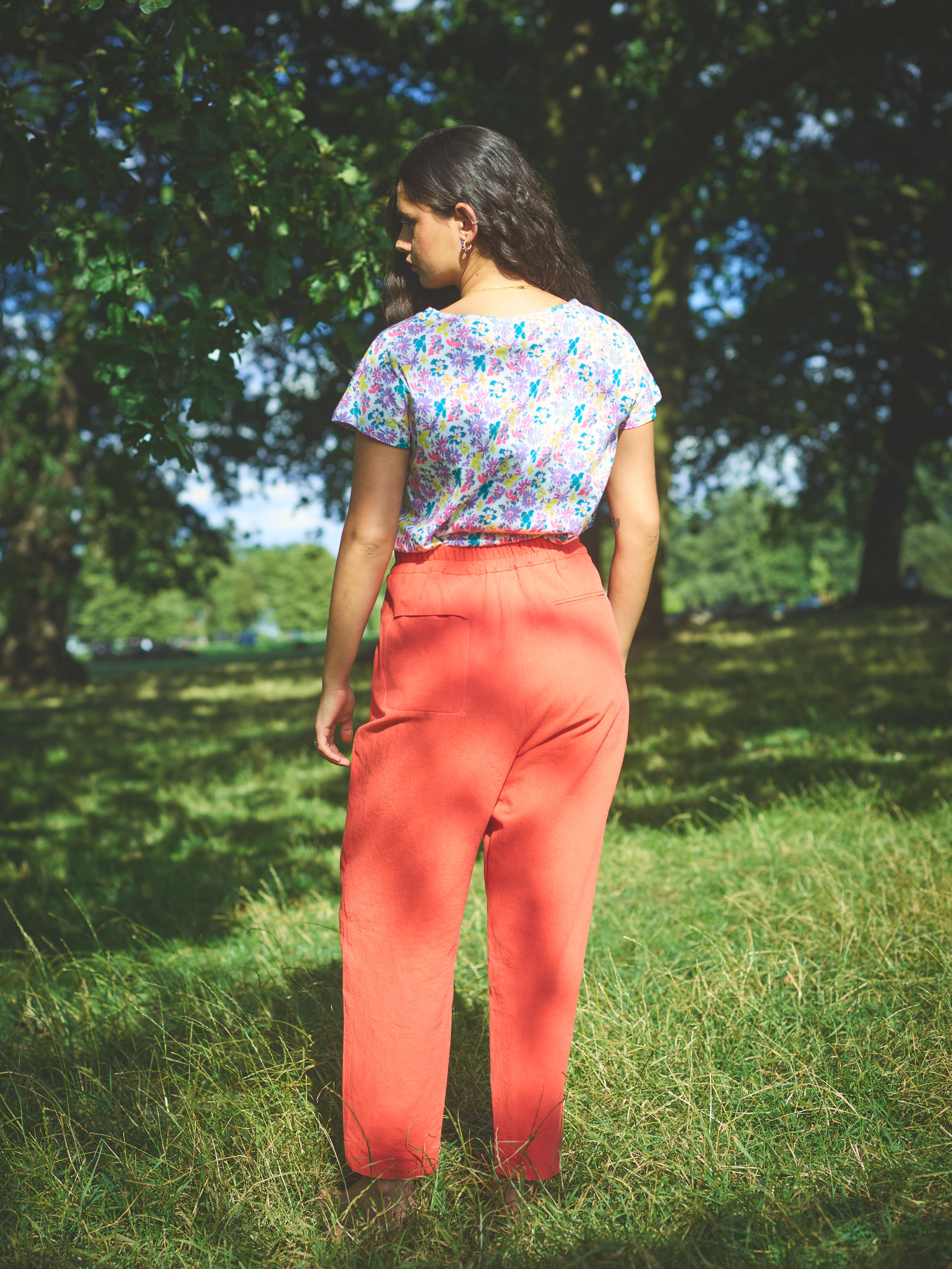 A pair of red cotton linen trousers with side welt pockets and a row of buttons down the front.