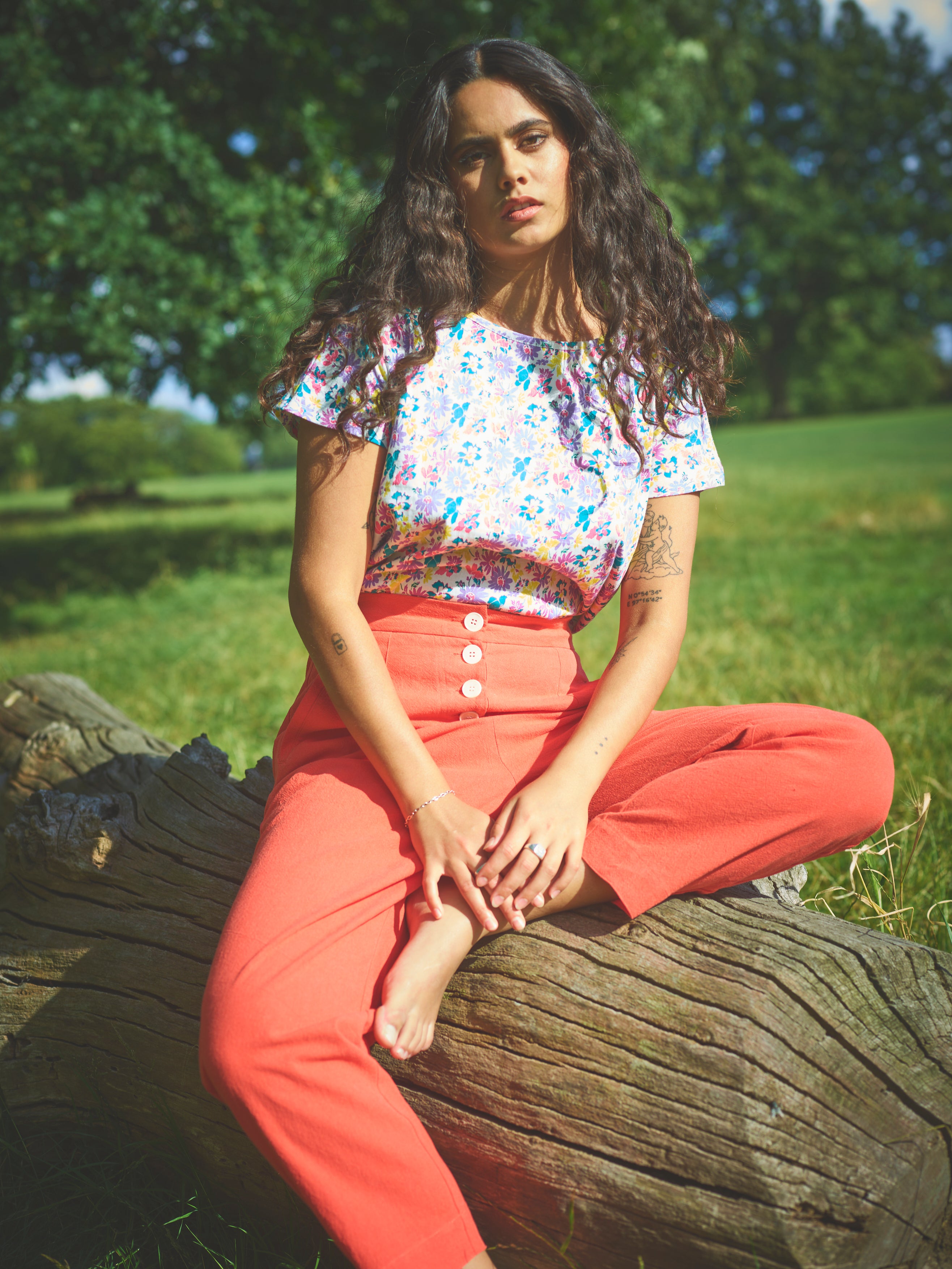A pair of red cotton linen trousers with side welt pockets and a row of buttons down the front.