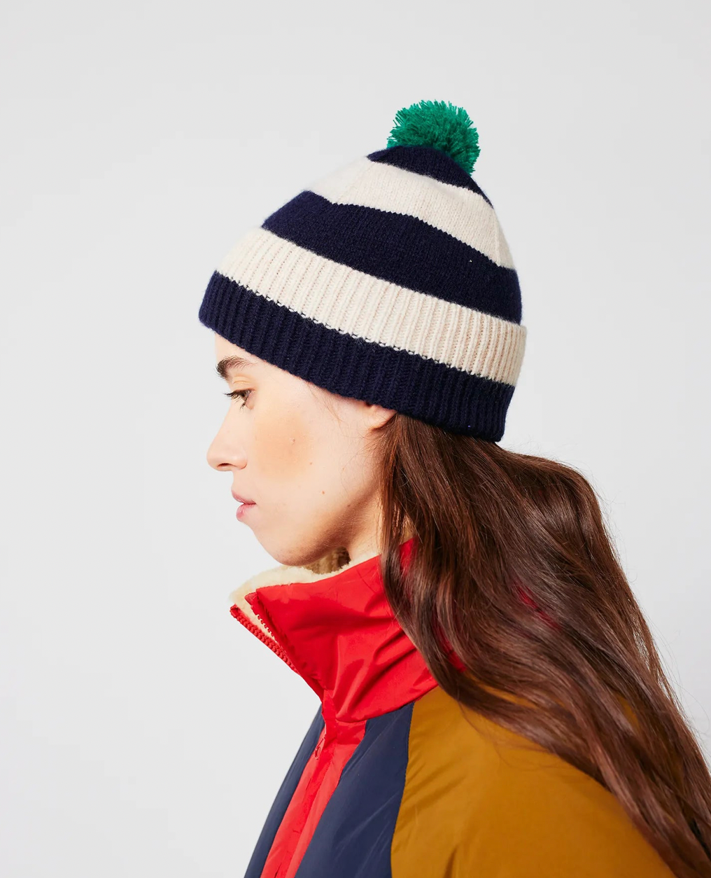 Person wearing a striped beanie with a pom-pom on a white background