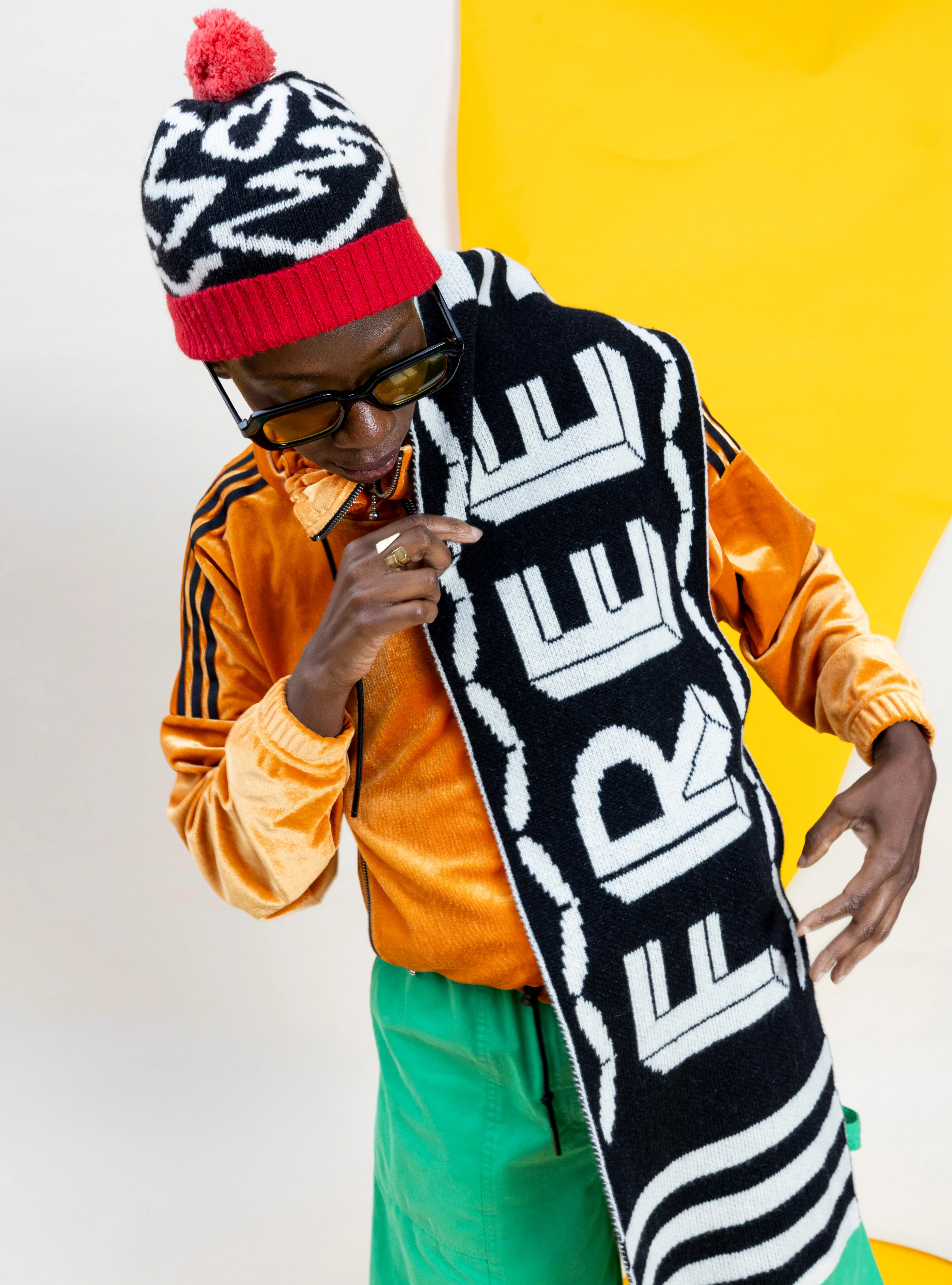 Person wearing a colorful outfit with a scarf that says 'FREE' against a yellow and white background