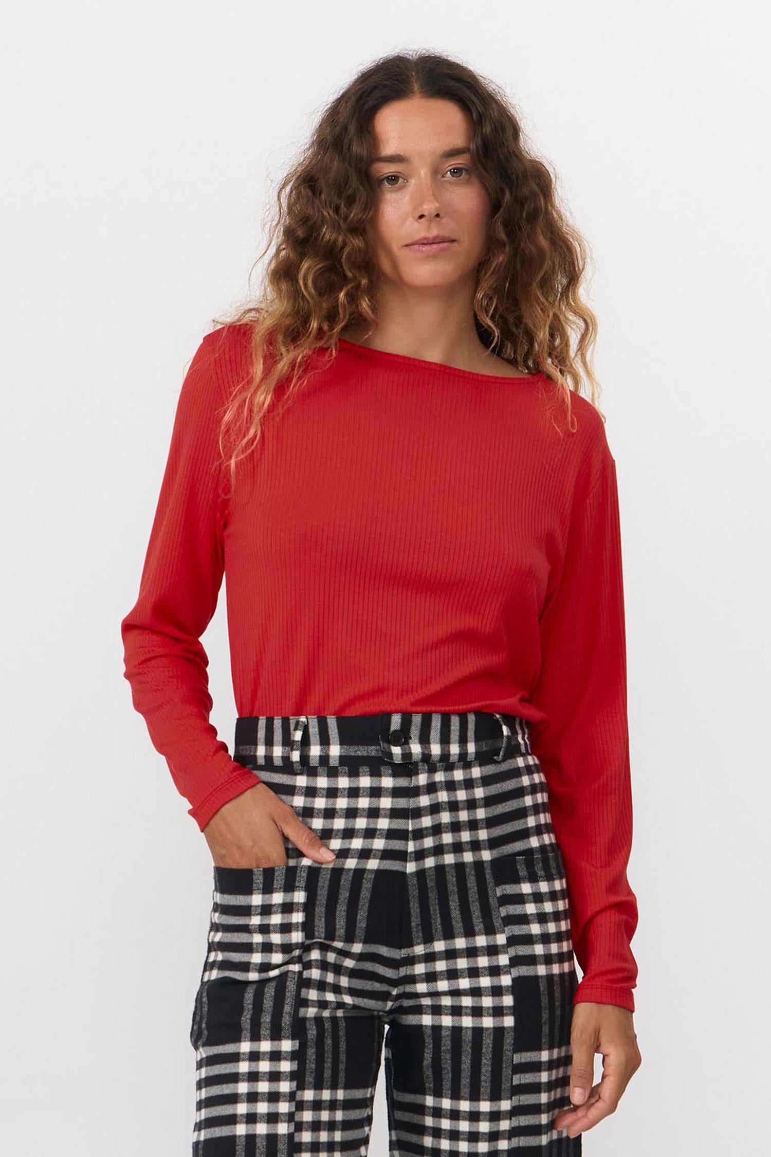 Woman wearing a red top and checkered pants on a white background