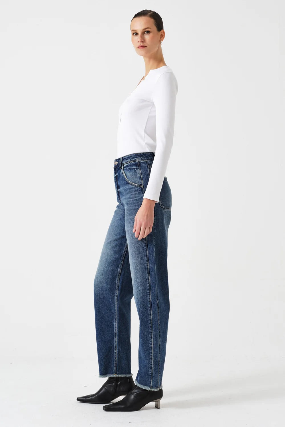 Person wearing a white top and blue jeans on a white background