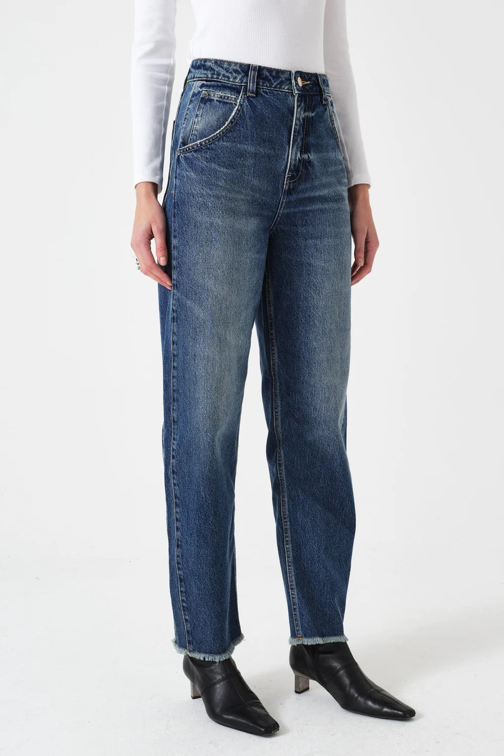 Person wearing blue jeans and black boots on a white background